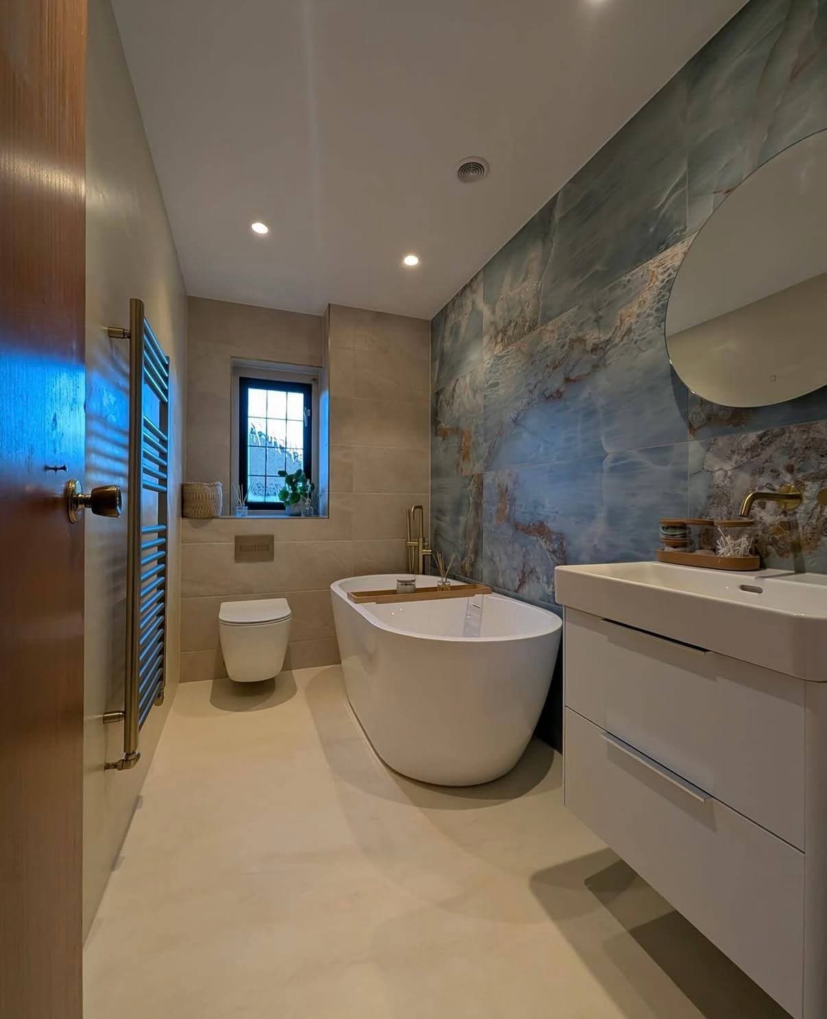 Bathroom remodel with blue stone feature wall, freestanding tub, and wall-mounted vanity