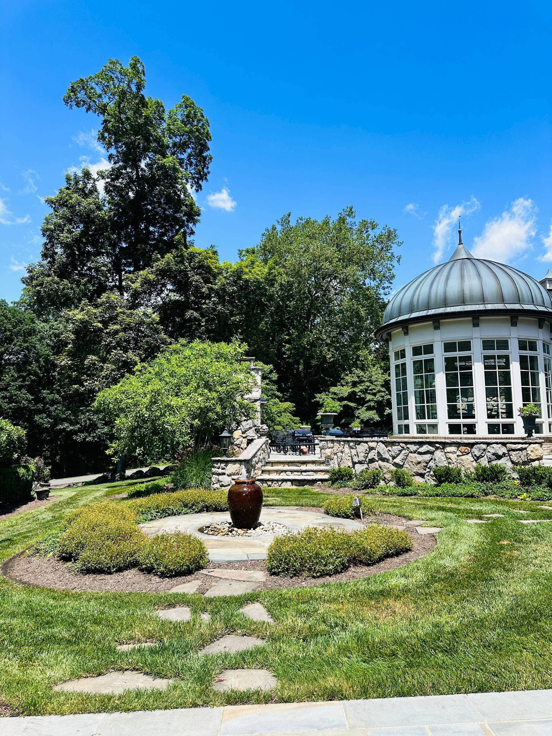 Finished garden pavilion with stone base, glass walls, landscaping, and lawn