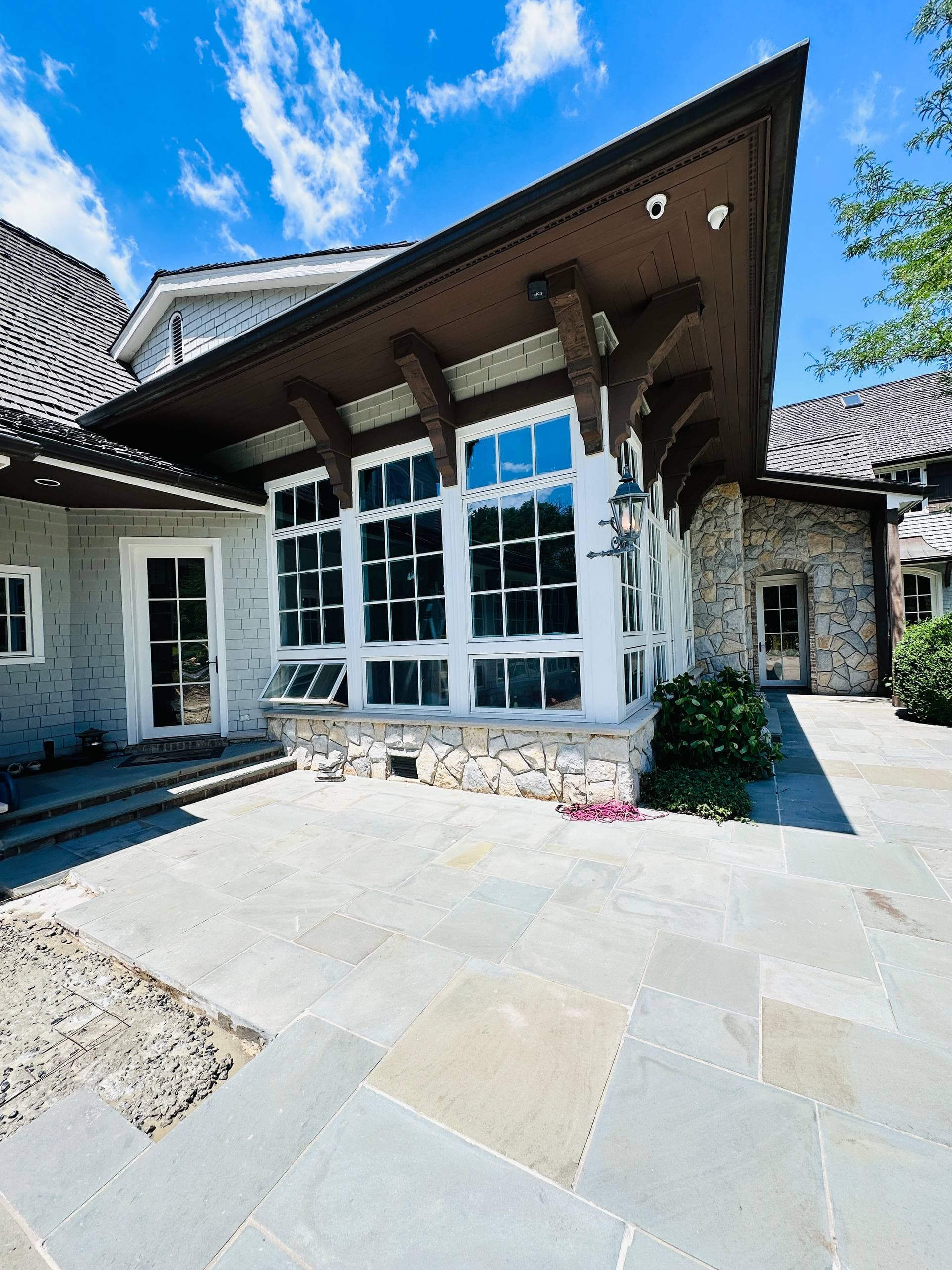 Exterior stone patio and window wall with detailed trim and roof overhang