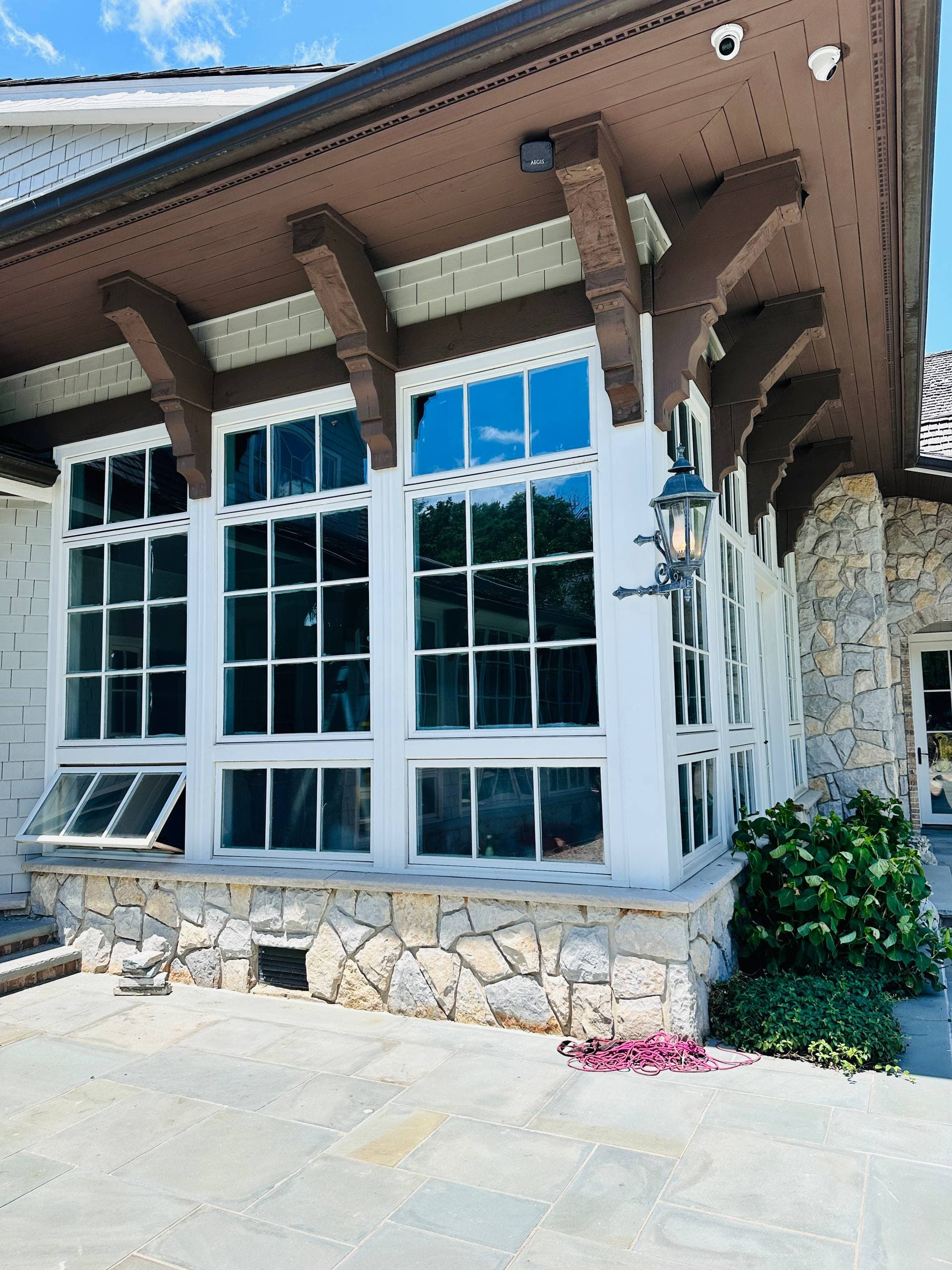 Exterior window wall with white trim, stone base, and brown roof detail