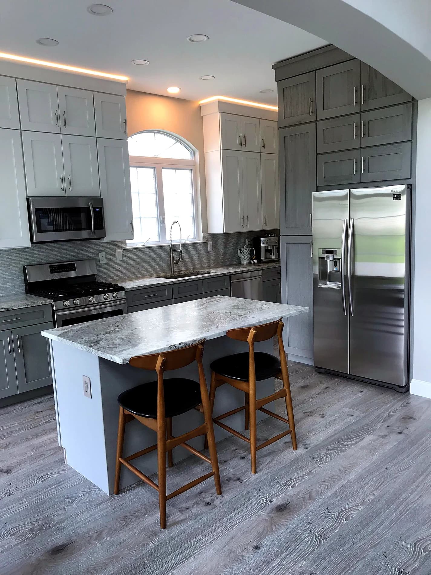 Finished kitchen with stone island, gray cabinetry, and bar seating
