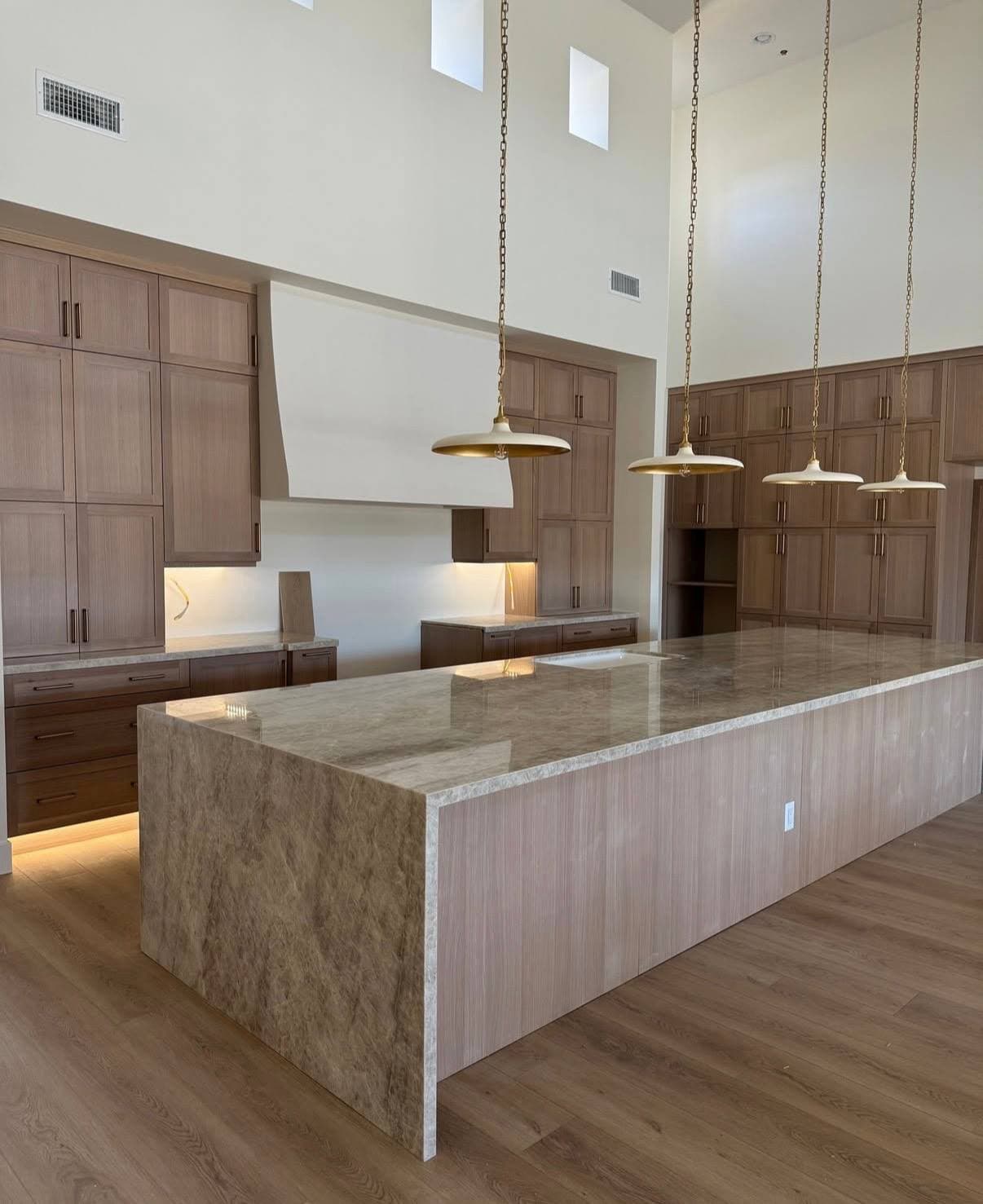 Tall kitchen with oak cabinetry, large stone island, and pendant lighting