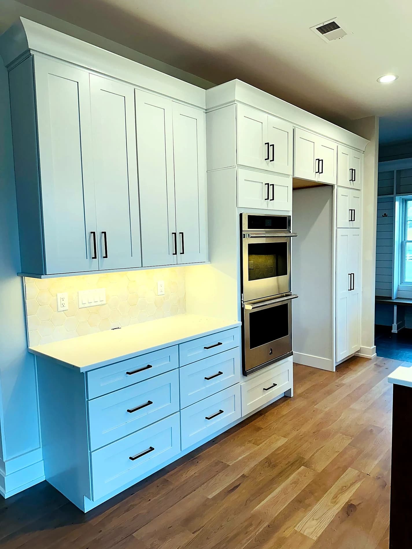 White cabinet kitchen wall with built-in appliances and under-cabinet lighting